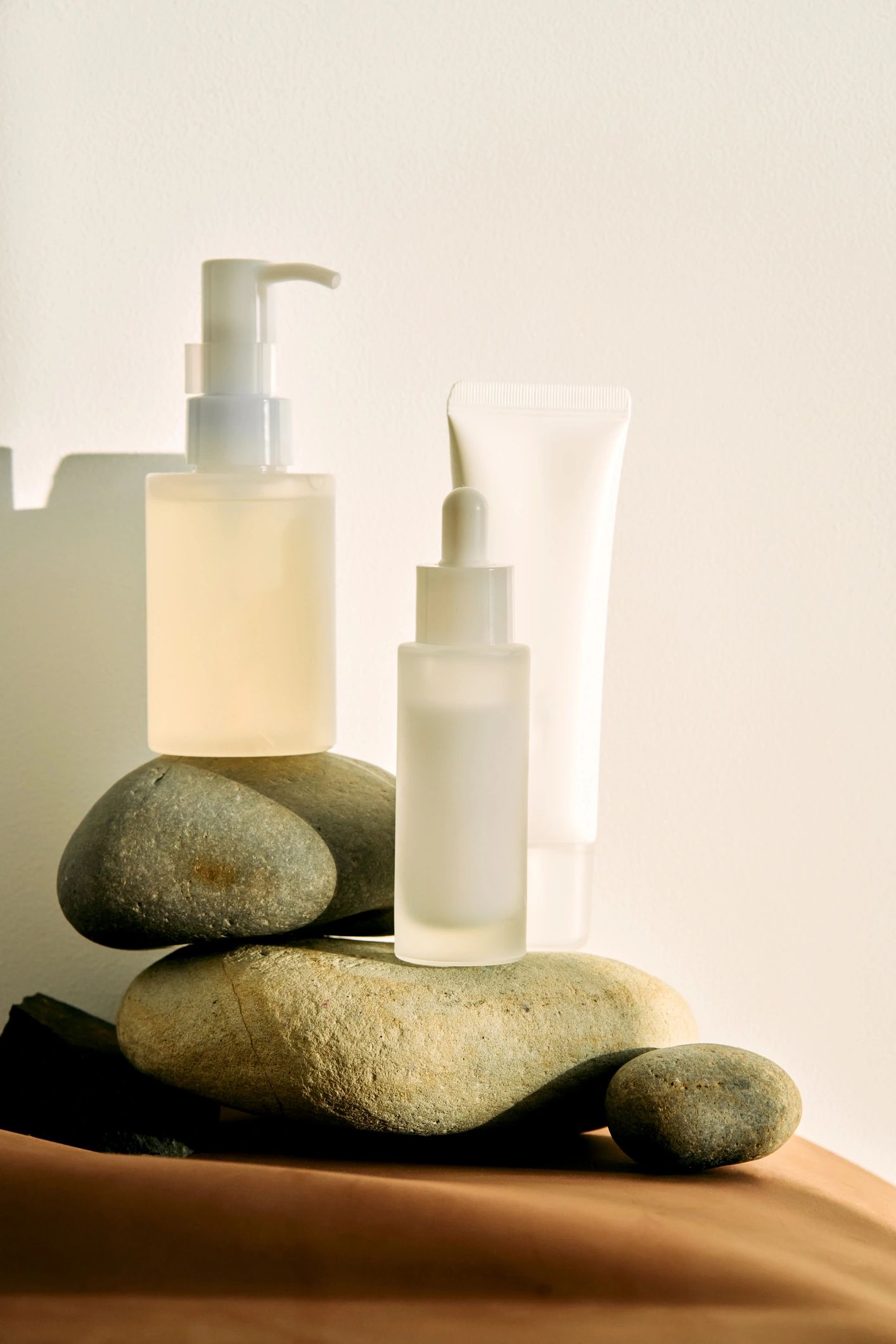 Skincare products balancing on natural stones in sunlight